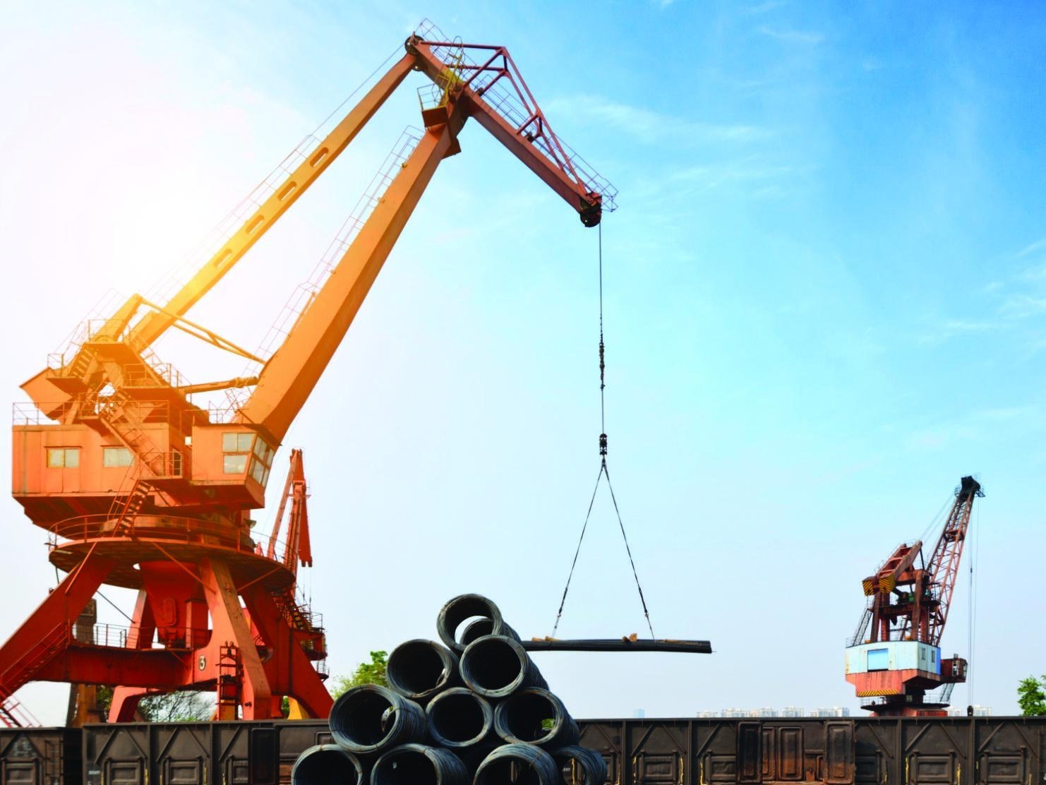 Crane handling large pipes in an industrial yard